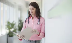 Médecin consultant un dossier, peut-être pour un deuxième avis médical et son remboursement.