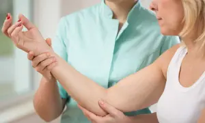 Une thérapeute examine le bras d'une patiente, possiblement pour une nevralgie cervico brachiale.