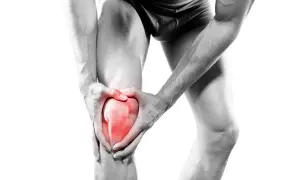 Homme tenant son genou rougeoyant, souffrant d'une douleur genou irradiant jambe.