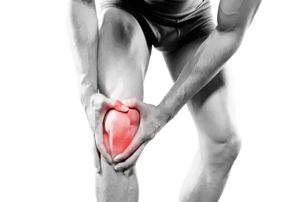 Homme tenant son genou rougeoyant, souffrant d'une douleur genou irradiant jambe.